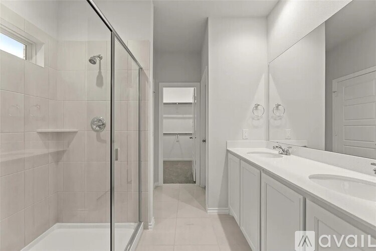 A bathroom with a walk-in shower and double sinks.