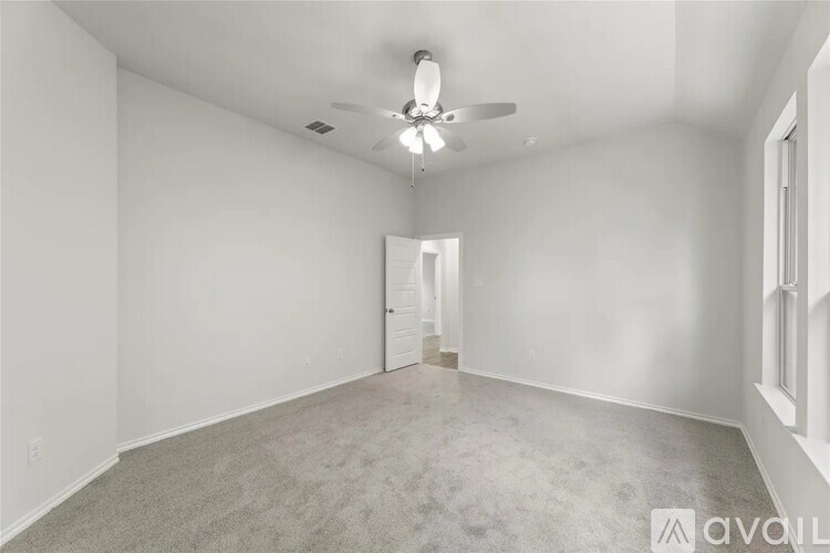 A spacious room with a ceiling fan and carpeted floor.