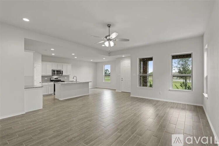 A spacious living room with a kitchen area in the background.
