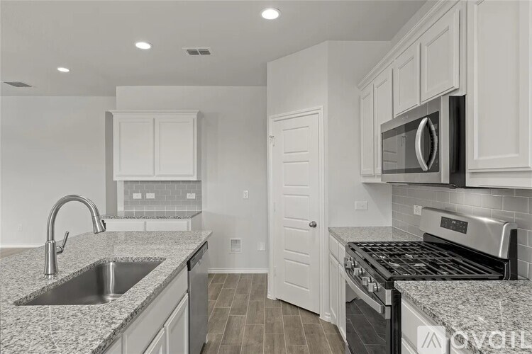 A kitchen with a sink, stove, and microwave.