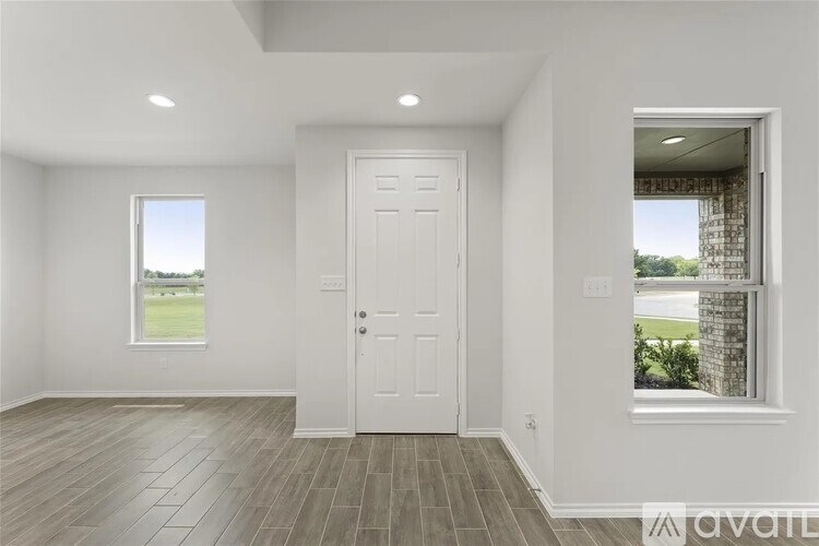 A room with a white door, window, and wooden flooring.