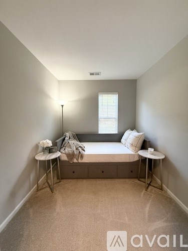 A bedroom with a bed, a table, and a lamp.