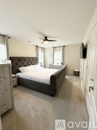 A bedroom with a large bed and a ceiling fan.