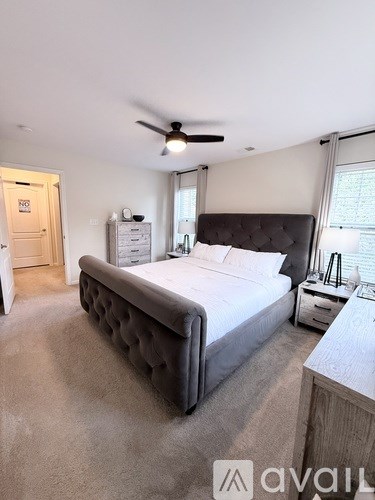 A bedroom with a large bed and a ceiling fan.
