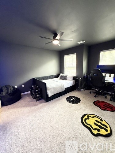 A bedroom with a bed, desk, and ceiling fan.