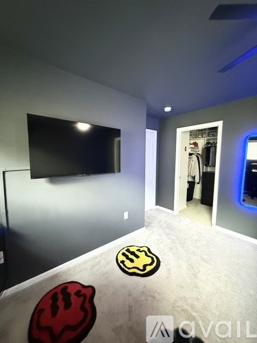 A room with a television, a doorway, and a logo on the floor.