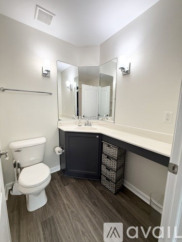 A bathroom with a toilet, sink, and mirror.