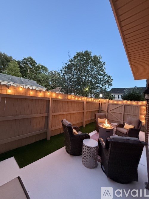 A backyard with a table, chairs, and string lights.