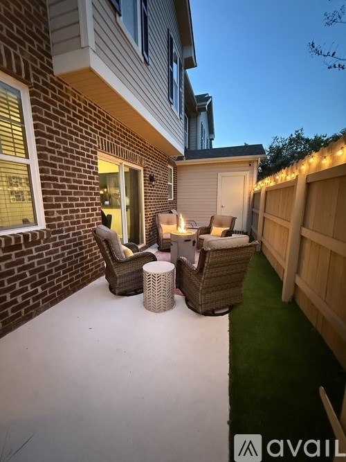 A patio with a table and chairs is lit up with string lights.