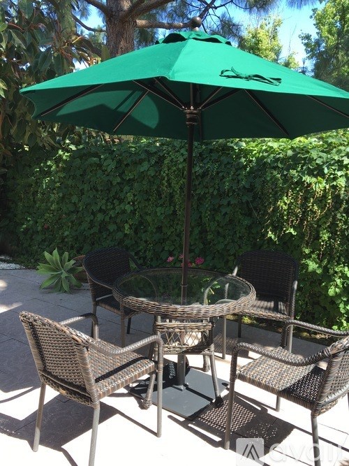 A patio with a green umbrella and chairs.