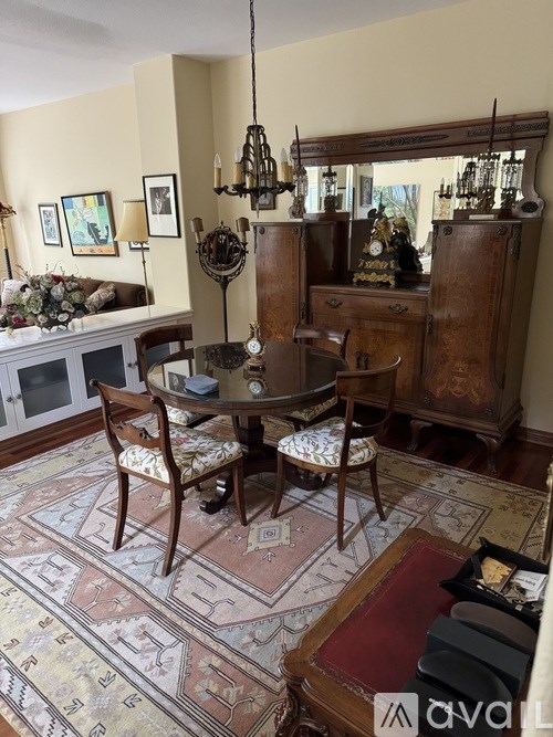 A dining room with a table surrounded by chairs and a chandelier hanging from the ceiling.