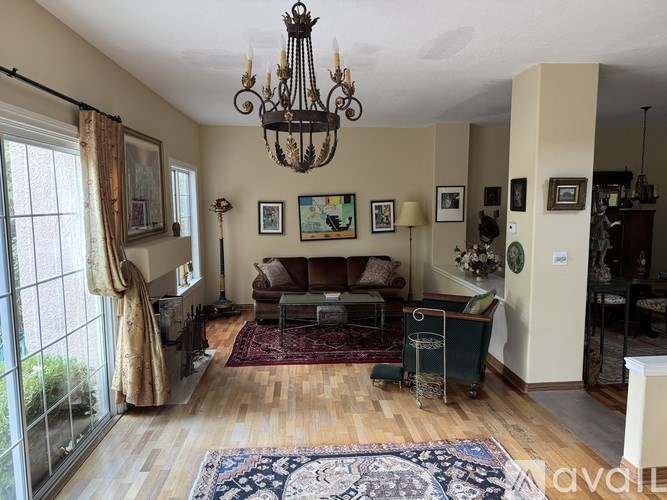 A living room with a chandelier, a couch, a rug, and pictures on the wall.