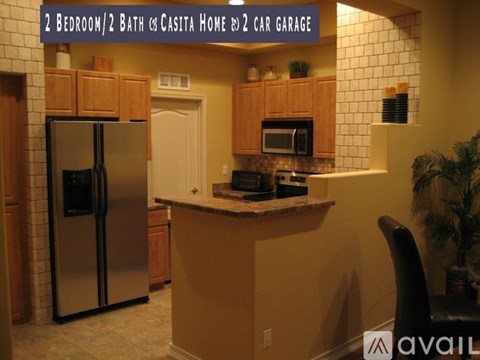 A kitchen with a refrigerator, microwave, and a counter with a sink.