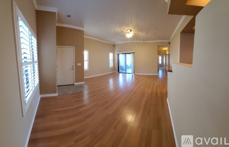 A spacious room with wooden flooring and a large window.