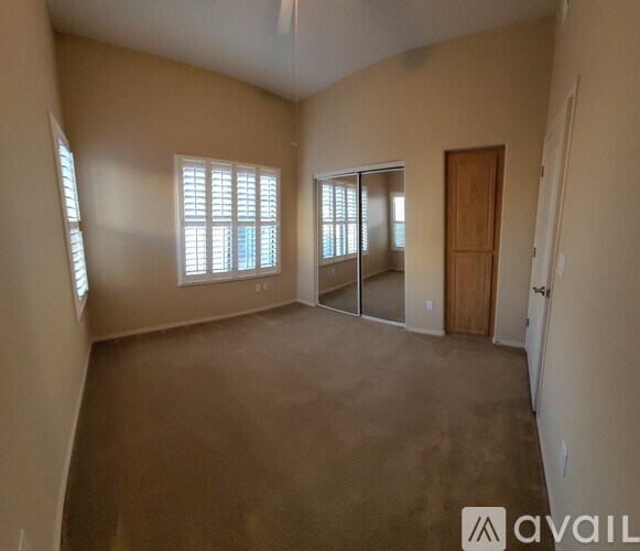 A spacious room with a brown carpet and a wooden door.