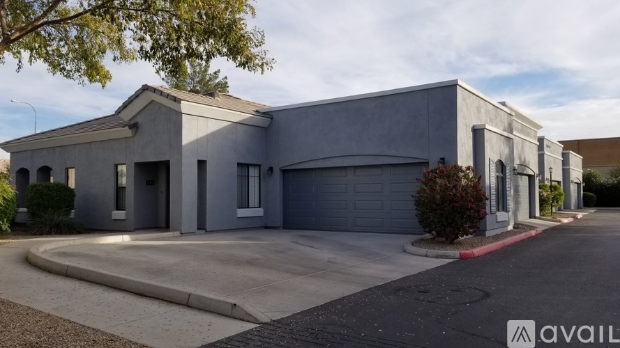 A modern two-story building with a garage door and a driveway in front.
