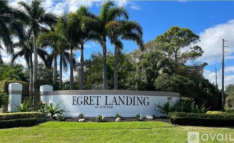 A sign that says "EGRET LANDING at JUPITER" in front of some trees.