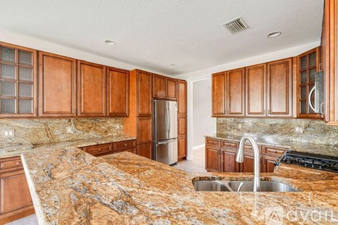 A kitchen with brown cabinets and granite countertops.