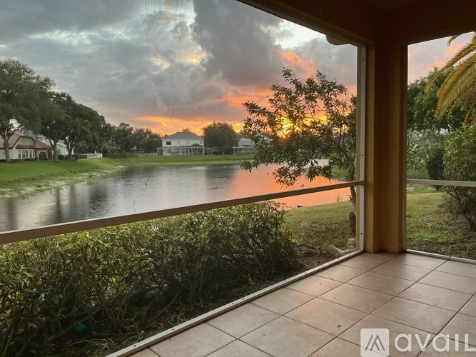 A balcony overlooks a body of water with a house and trees in the distance.
