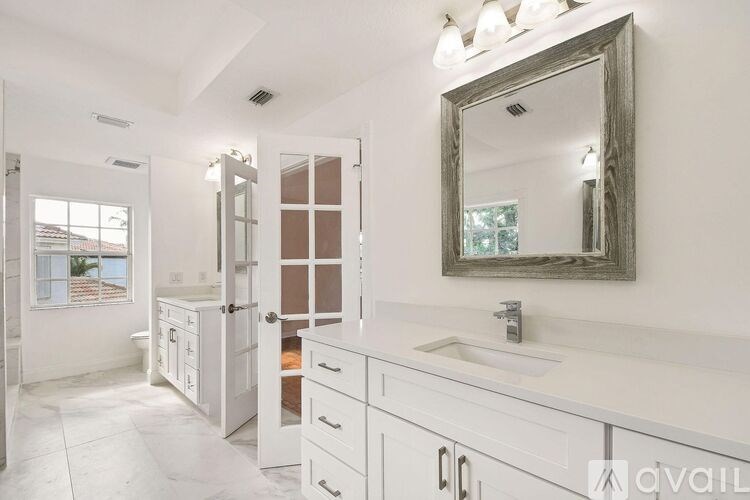 A bathroom with a white vanity and a mirror.