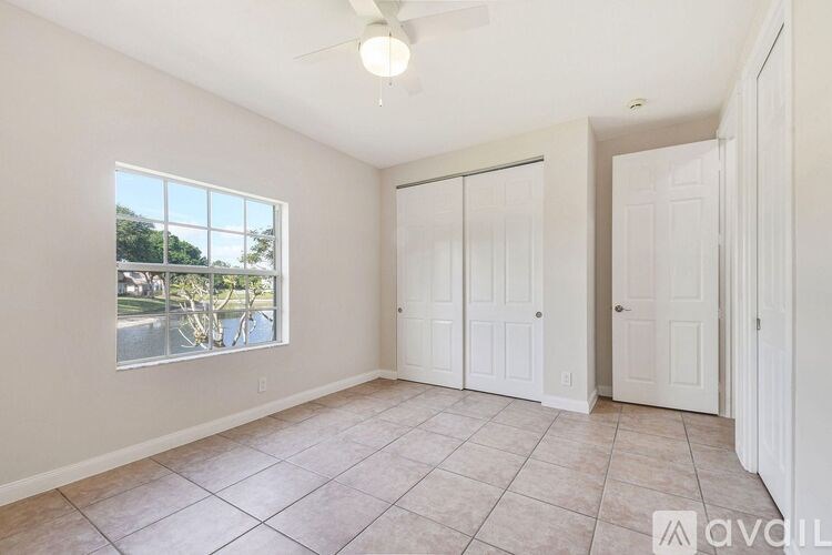 A room with a window, tiled floor, and a ceiling fan.