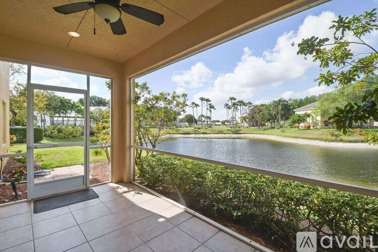 A patio with a ceiling fan and sliding glass doors overlooking a lake.
