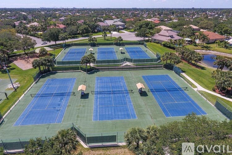 A tennis court surrounded by a green fence and trees.