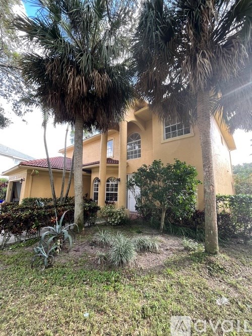 A house with a red roof and a palm tree in front.