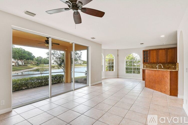 A spacious room with a ceiling fan and sliding glass doors leading to a view of a lake.