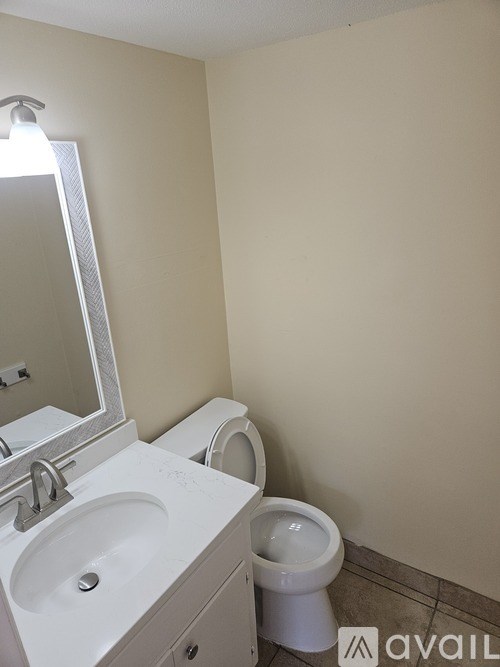 A bathroom with a toilet, sink, and mirror.