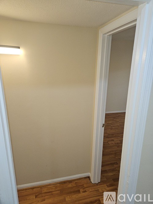 A room with a white door and wooden floor.