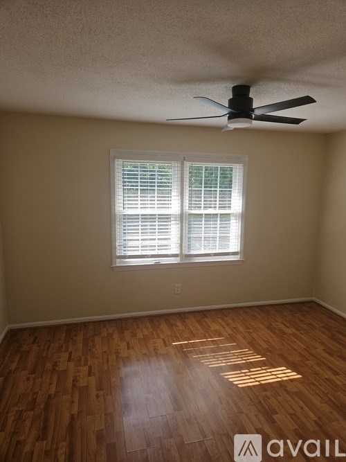 A room with a ceiling fan and wooden flooring.