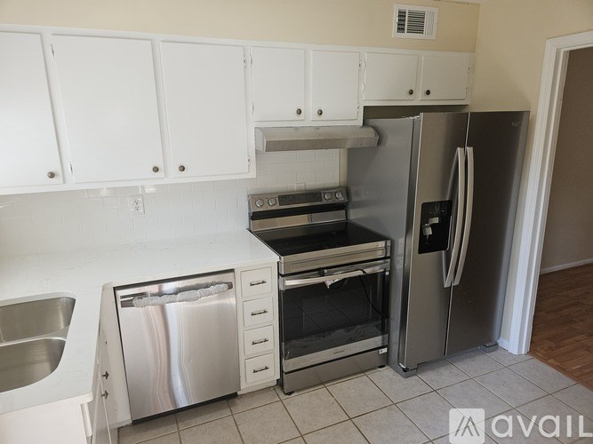 A kitchen with white cabinets and a stainless steel refrigerator.