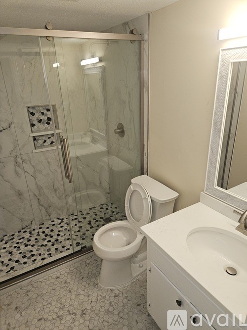 A bathroom with a toilet, sink, and walk-in shower.