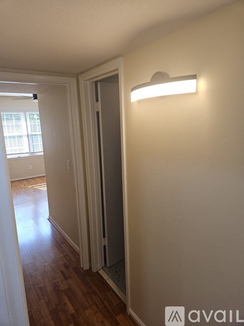 A hallway with a light on the wall and a door at the end.