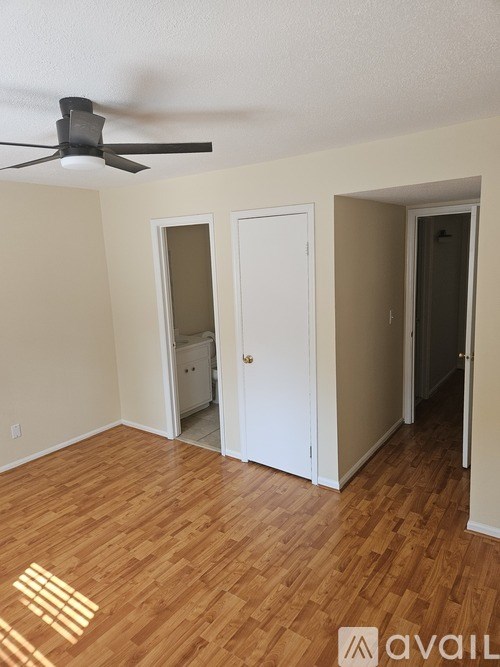 A room with a ceiling fan and wooden flooring.