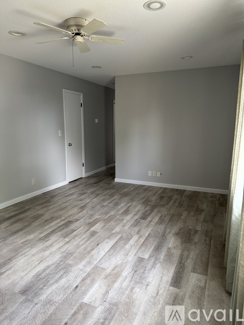 A room with a ceiling fan and wooden flooring.