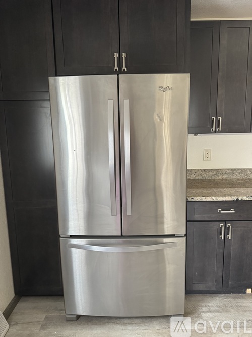A stainless steel refrigerator with two doors stands in a kitchen.