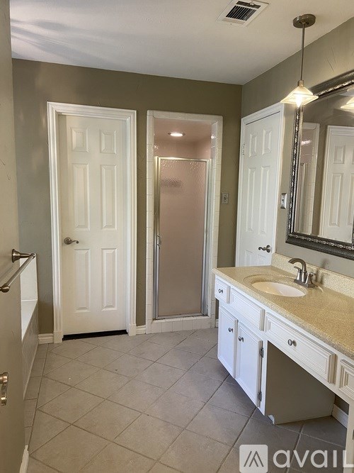 A bathroom with a white door, a sink, and a mirror.