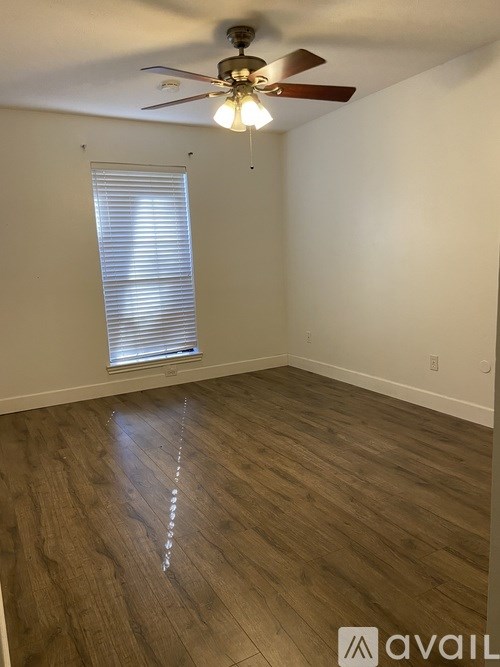 A room with a ceiling fan and a window with blinds.