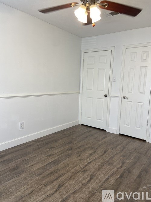 A room with a ceiling fan and two doors.