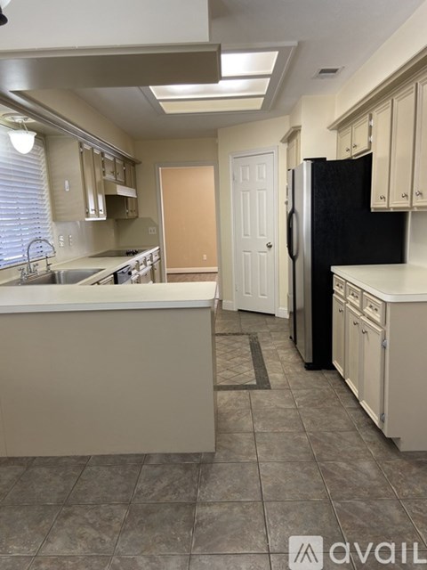 A kitchen with a black refrigerator and white cabinets.