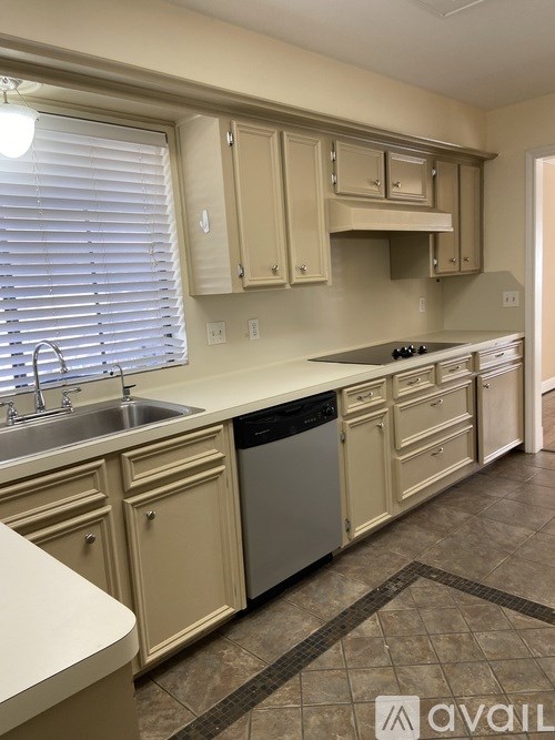 A kitchen with beige cabinets and a sink.