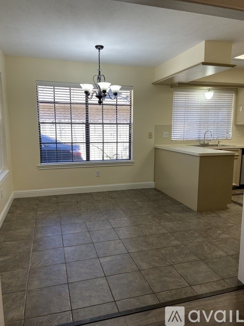 A kitchen area with a sink and a window with blinds.