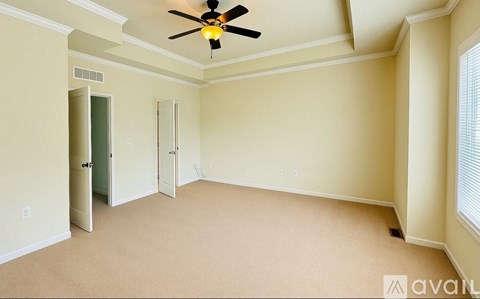 A room with a ceiling fan and carpeted floor.