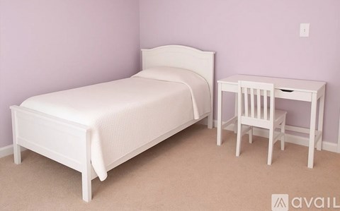 A white bed and desk set in a room.