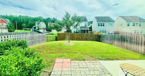 A backyard with a wooden fence and a green lawn.