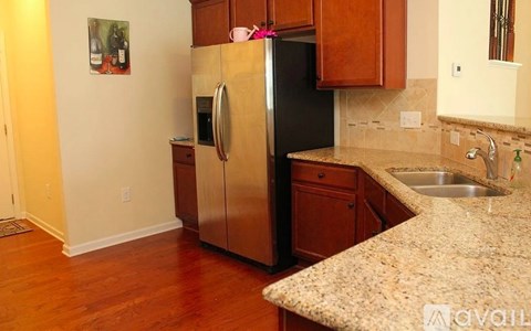 A kitchen with a refrigerator, sink, and wooden cabinets.