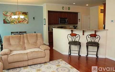 A living room with a brown couch and two chairs.