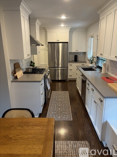 A kitchen with white cabinets and a stainless steel refrigerator.